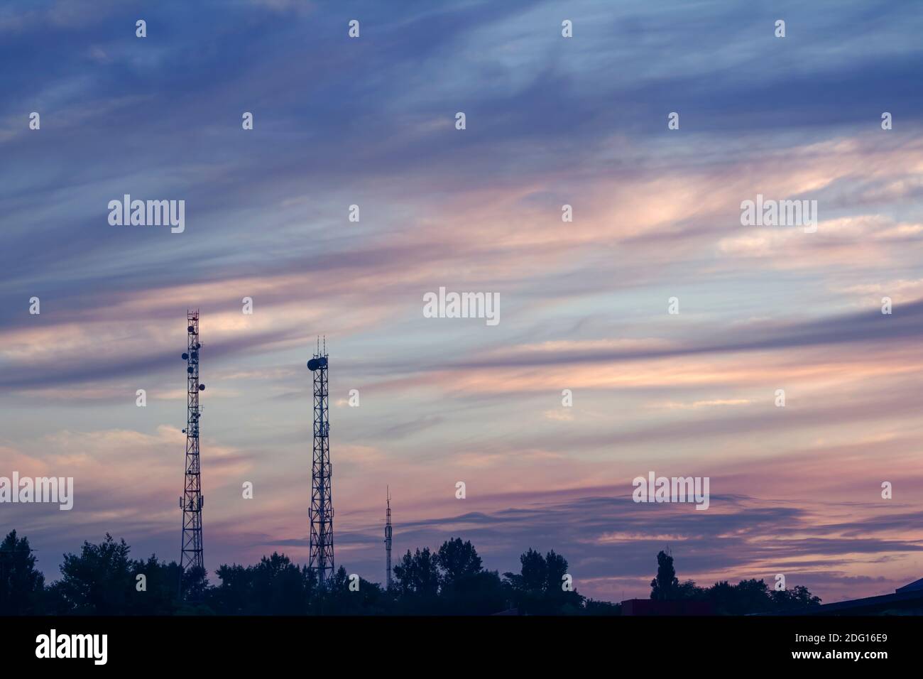 Abendsommerlandschaft mit zwei hohen Telekommunikationstürmen im Hintergrund Von bewölktem Sonnenuntergang Stockfoto