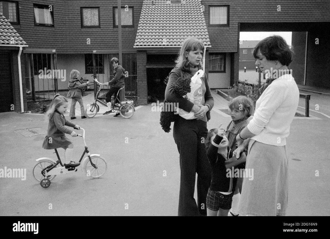 Wohnsiedlung aus den 1970er Jahren Großbritannien. Zwei einheimische Frauen mit Kindern unterhalten sich in der autofreien Straße. Kinder spielen auf ihren Fahrrädern. 1977 England. Milton Keynes ist eine neue Stadt, eine moderne Wohnsiedlung Buckinghamshire HOMER SYKES Stockfoto