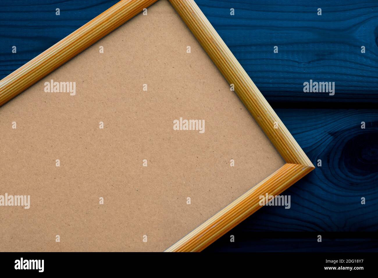Leerer beiger Holzrahmen mit antikem Papier auf der dunkelblauen Oberfläche der Holzlatten. Platz kopieren, Draufsicht. Weihnachtsthema. Stockfoto