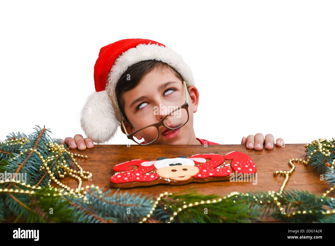 Ein Junge von 10-13 Jahren in einem roten Weihnachtshut wartet auf das neue Jahr oder Weihnachten. Junge rollt die Augen. Warten auf Weihnachten Nacht, Urlaub Stockfoto