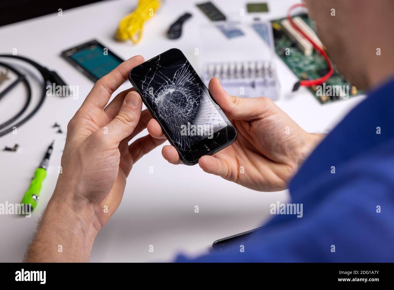 Smartphone mit gebrochenem Bildschirm in den Händen des Technikers geknackt. Telefon Reparaturservice Stockfoto