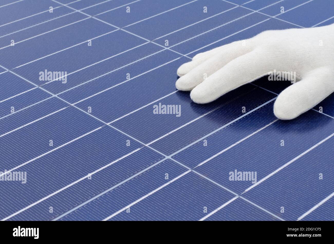 Hand mit weißem Handschuh vor Solarzellen Stockfoto