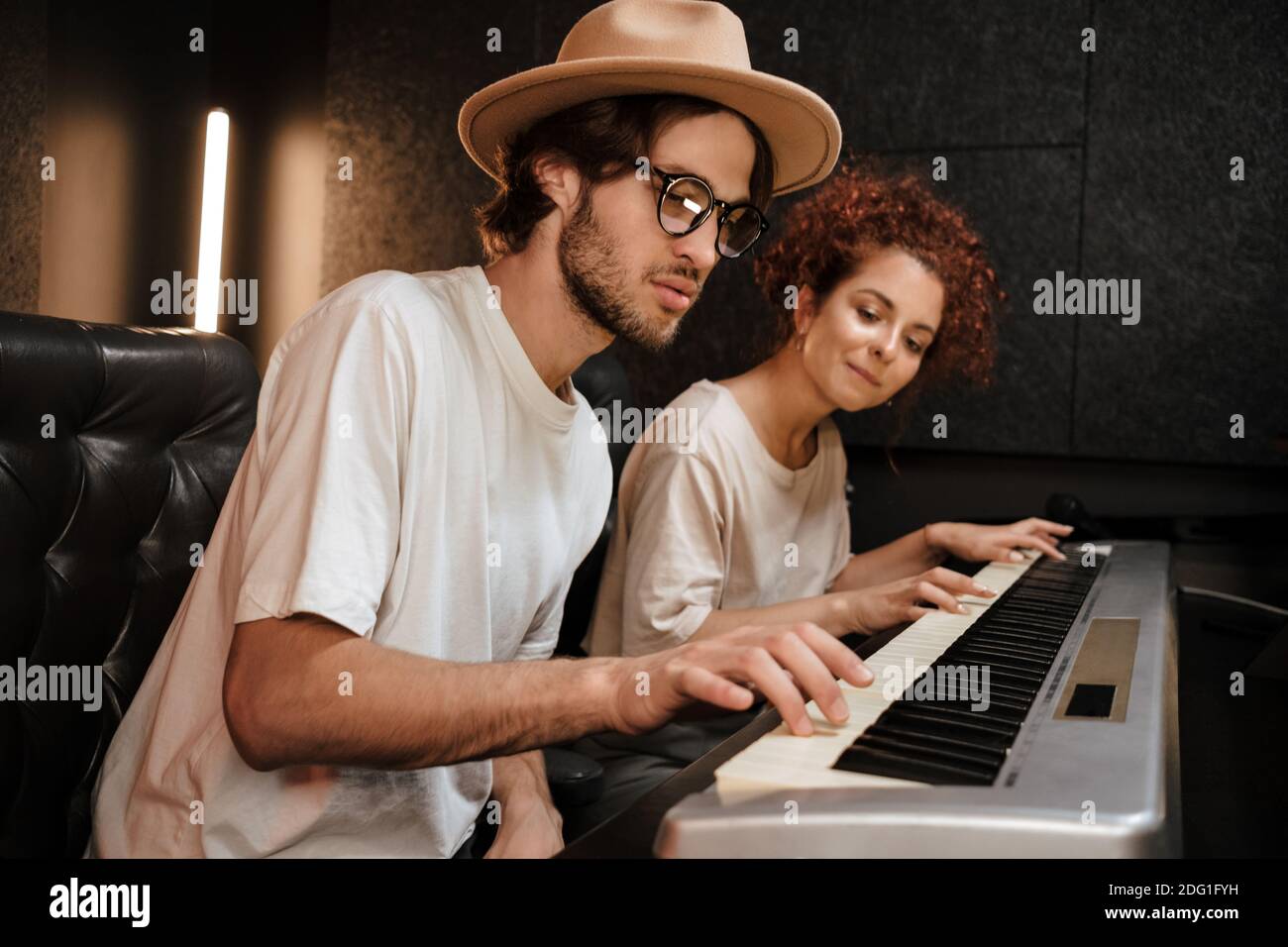 Junge stilvolle paar Musiker traumartig komponieren Musik auf Klavier Keyboard arbeitet im modernen Aufnahmestudio zusammen Stockfoto