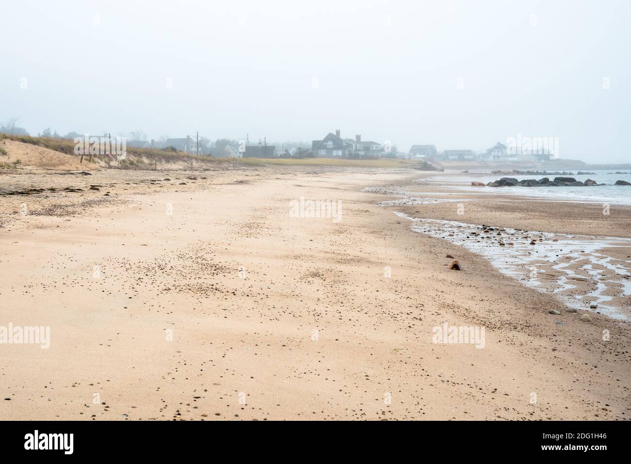 Leerer Sandstrand an einem nebligen Herbsttag. Oceanfront Eigenschaften sind im Hintergrund sichtbar. Stockfoto