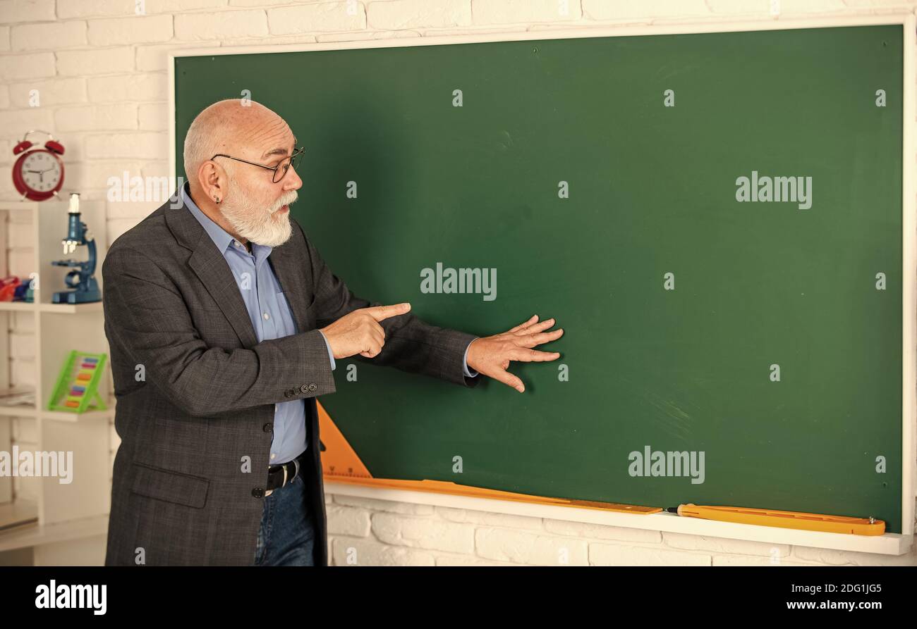 Beobachten und lernen. Bildung in der modernen Schule. Bärtiger Mann zeigen etwas. Kopie spce. Senior Lehrer erklären Thema an der Tafel. Lehrer der Geographie. Klassenzimmer mit Karte. Zurück zur Schule. Stockfoto