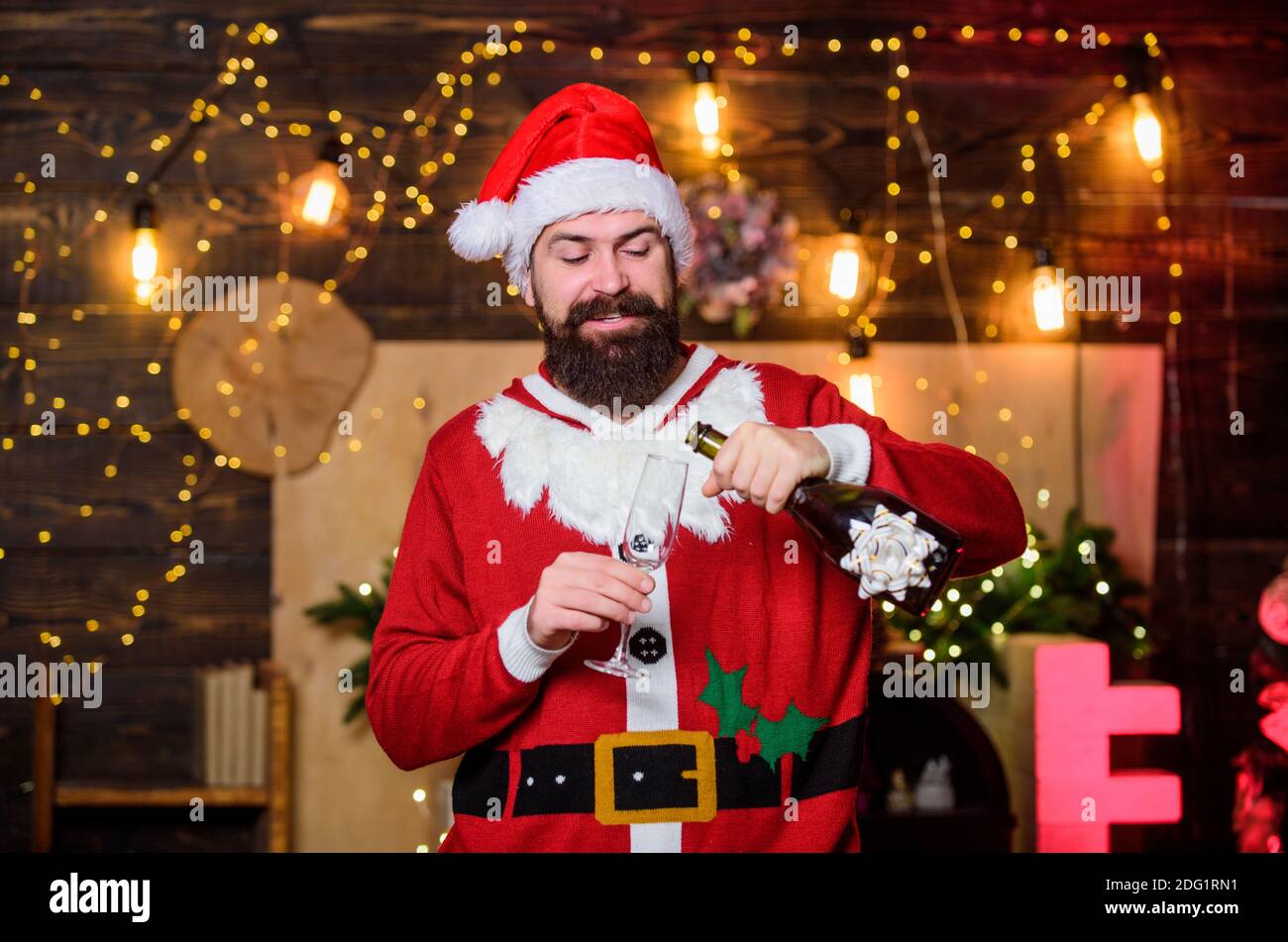 Sei glücklich. weihnachtsmann Champagner-Flasche. Winterfeier. Winterferien. Warten Sie auf Weihnachtsgeschenke. frohe weihnachten. Mann weihnachtsmann Hut. Neujahr Geschenke. weihnachtsdekoration. Glücklich bärtigen Mann Elf. Stockfoto