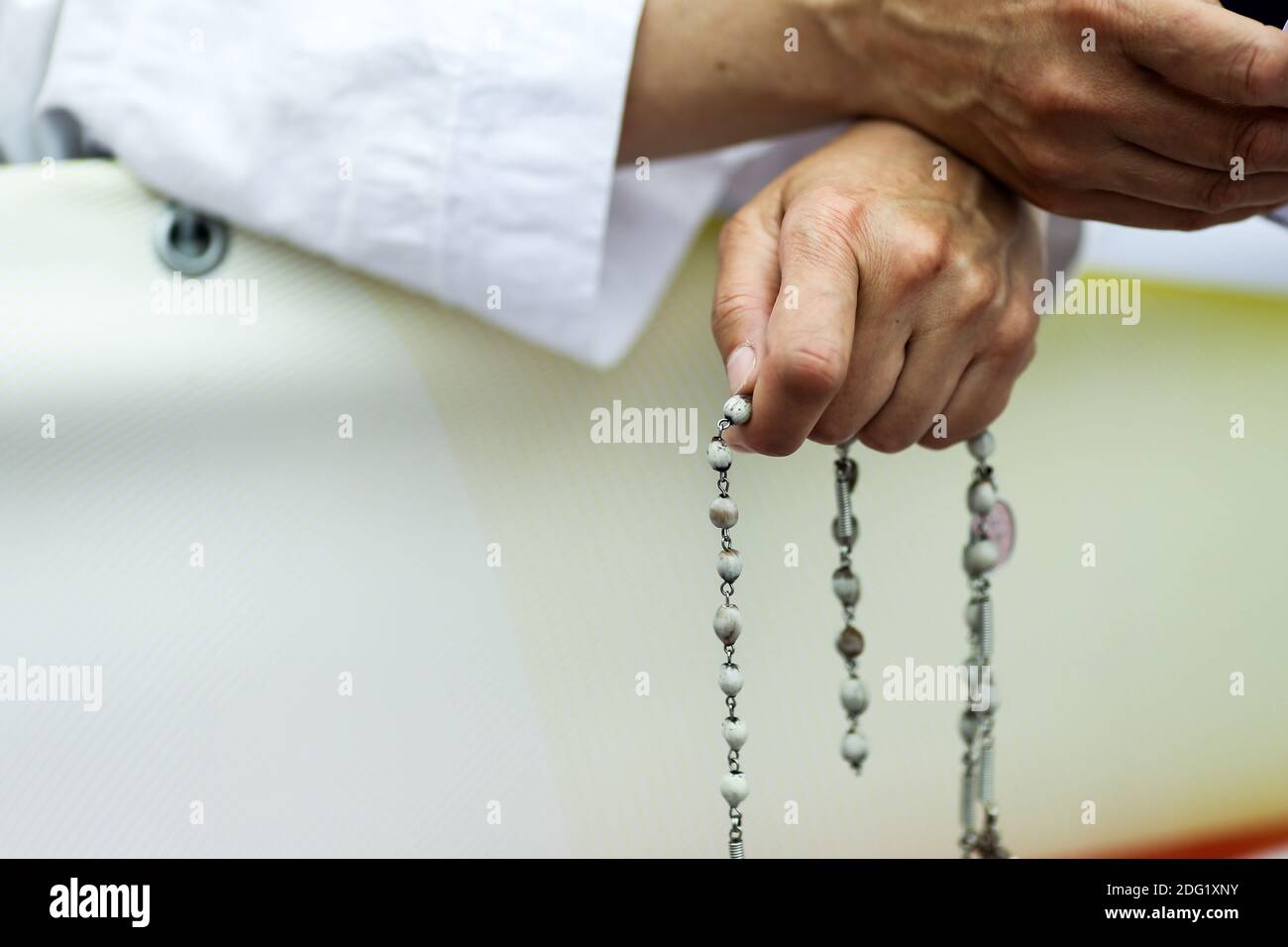 Artikeldetails mit den Händen einer katholischen Nonne, die einen Rosenkranz hält. Stockfoto
