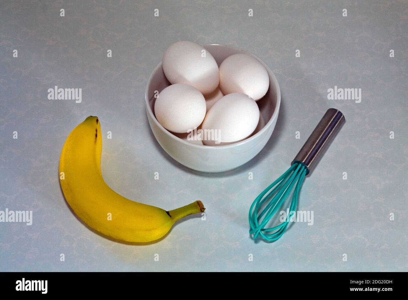 Frische Eier, ein Rührgerät, eine Banane und eine Eieruhr, um ein gesundes Frühstück vorzubereiten. Stockfoto
