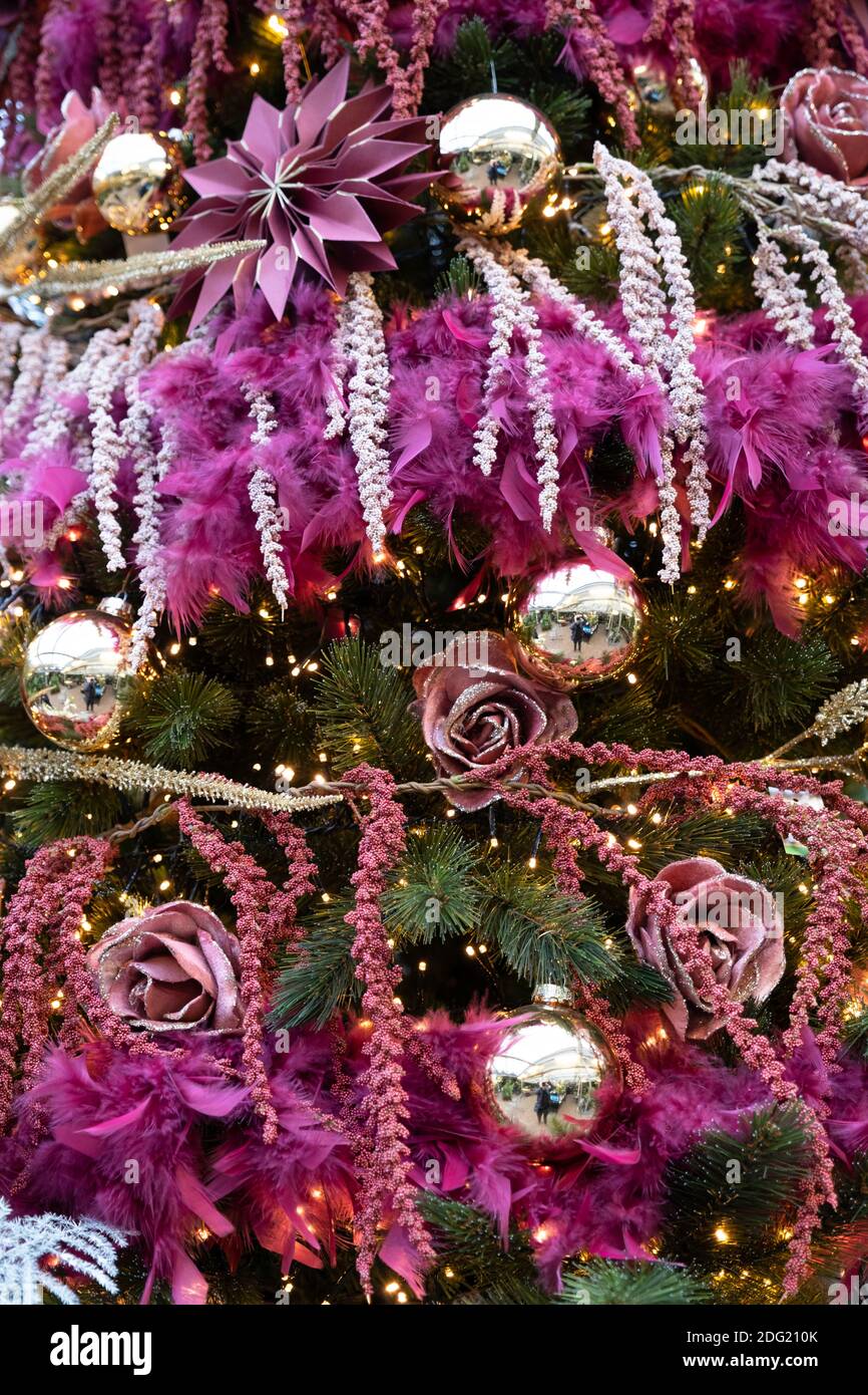 Dekorative Kugeln, Bänder und Girlanden hängen von einem künstlichen Baum, alles in violetten und violetten Tönen. Verkündet den Geist und die Freude von Weihnachten. Stockfoto