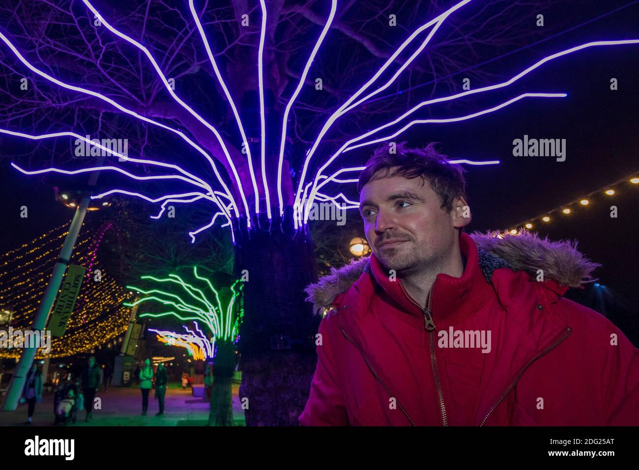 London, Großbritannien. Dezember 2020. Der Künstler David Ogle vor seiner Arbeit "Lumen", Bäume mit leuchtendem Neon-Flex beleuchtet. Vorschau von „Winter Light“ präsentiert vom Southbank Centre. Bis Ende Februar 2021 sind rund um die Gebäude und den Riverside Walk über 15 Kunstwerke und neue beleuchtete Auftragsarbeiten führender internationaler Künstler zu sehen. Kredit: Stephen Chung / Alamy Live Nachrichten Stockfoto