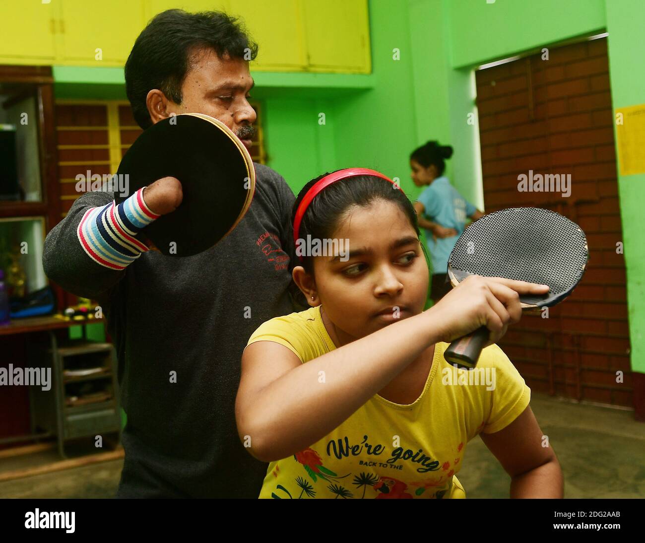 Kajol Dey, ein 49-jähriger behinderter Tischtennisspieler und Trainer, wird am Internationalen Tag der Menschen mit Behinderungen (IDPD) gesehen, wie er ein junges Mädchen trainiert. Agartala, Tripura, Indien. Stockfoto