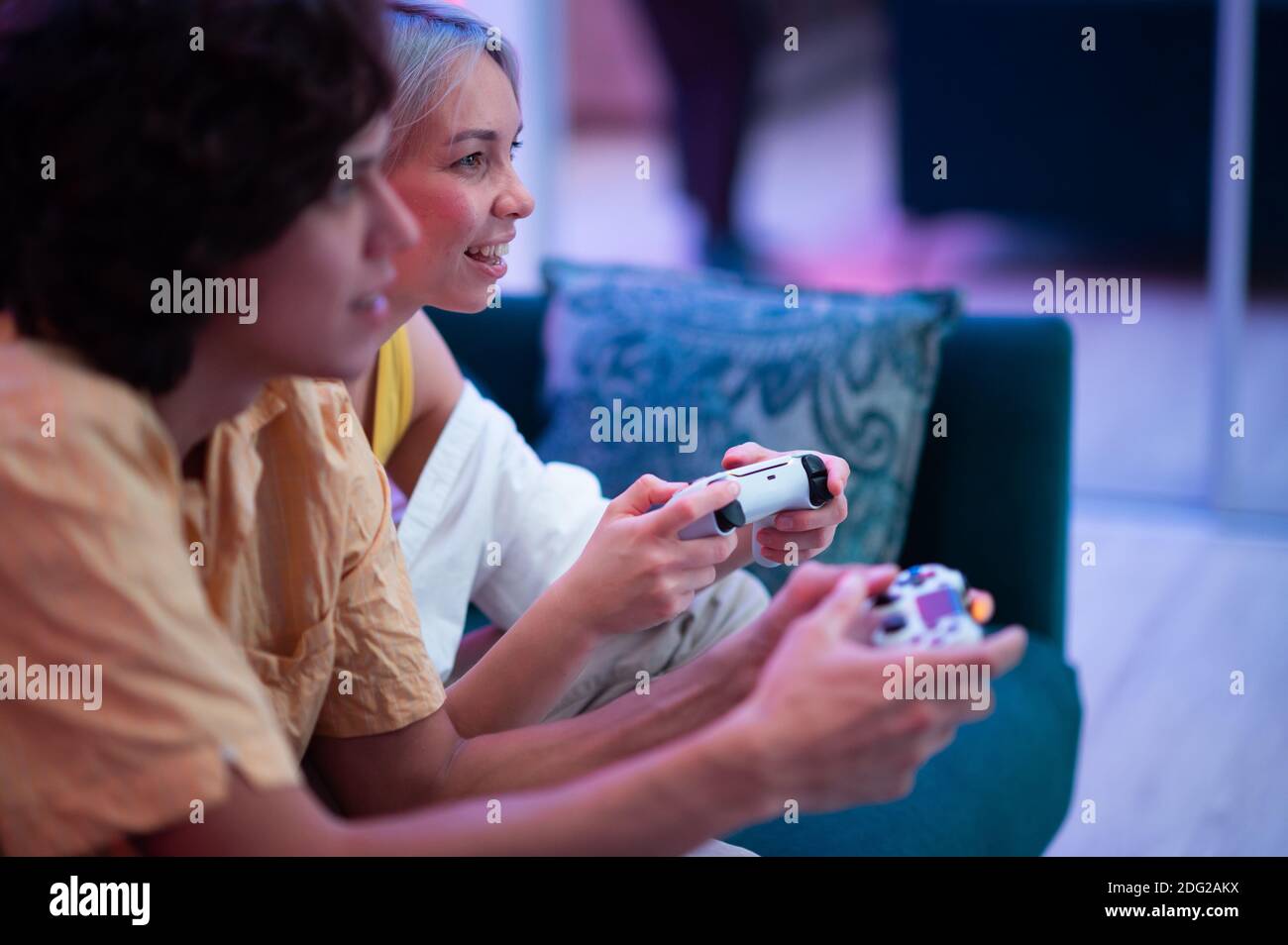 Lächelndes Paar hält Gamepads spielen Videospiel zu Hause. Junge Menschen verbringen Zeit zusammen während der Selbstisolation gegen Pandemie. Stockfoto