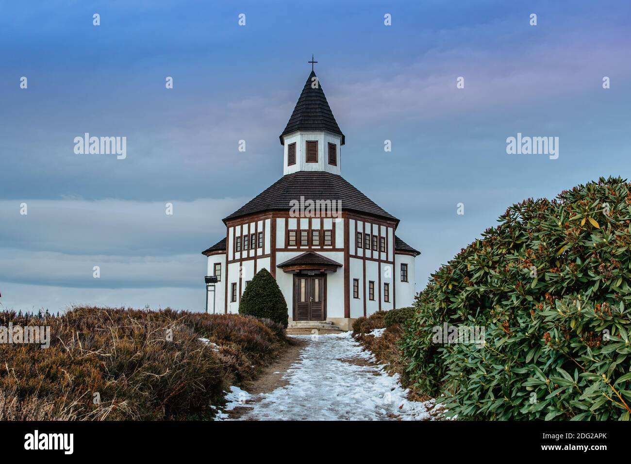 Kleine weiße ländliche Tesarovska Kapelle mit Friedhof im Dorf Korenov, Isergebirge, Tschechische Republik. Blick auf die Winterlandschaft bei Sonnenuntergang.Wald Stockfoto