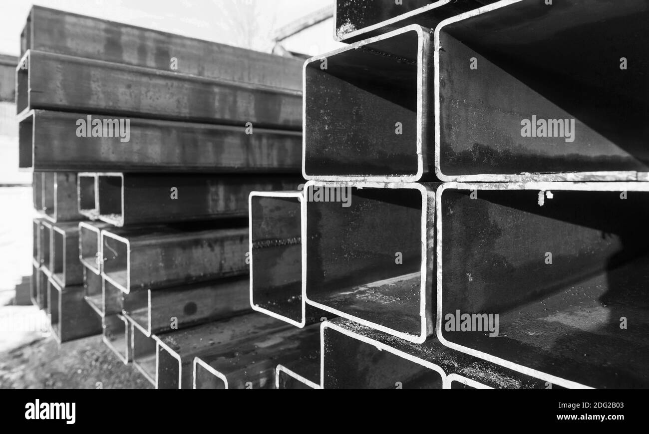 Stapel von gewalzten Metallprodukten, nassen Stahlrohren mit rechteckigem Querschnitt, Nahaufnahme schwarz-weiß Foto mit selektivem Weichfokus Stockfoto