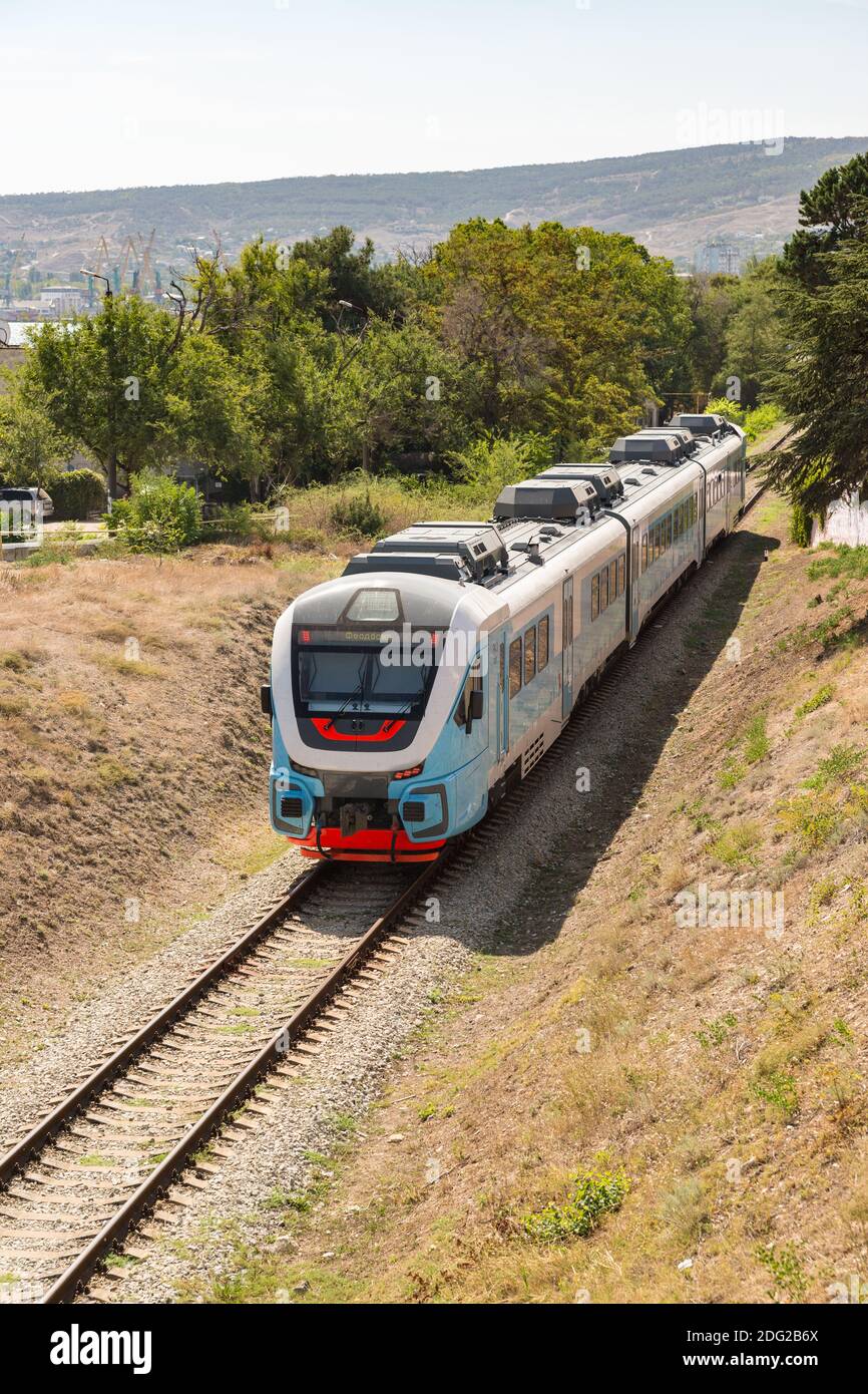 Russland, Krim, Feodosia 18. September 2020-eine elektrische Lokomotive mit Personenwagen fährt durch die Stadt zum Bahnhof. Das Auto leuchtet auf Stockfoto