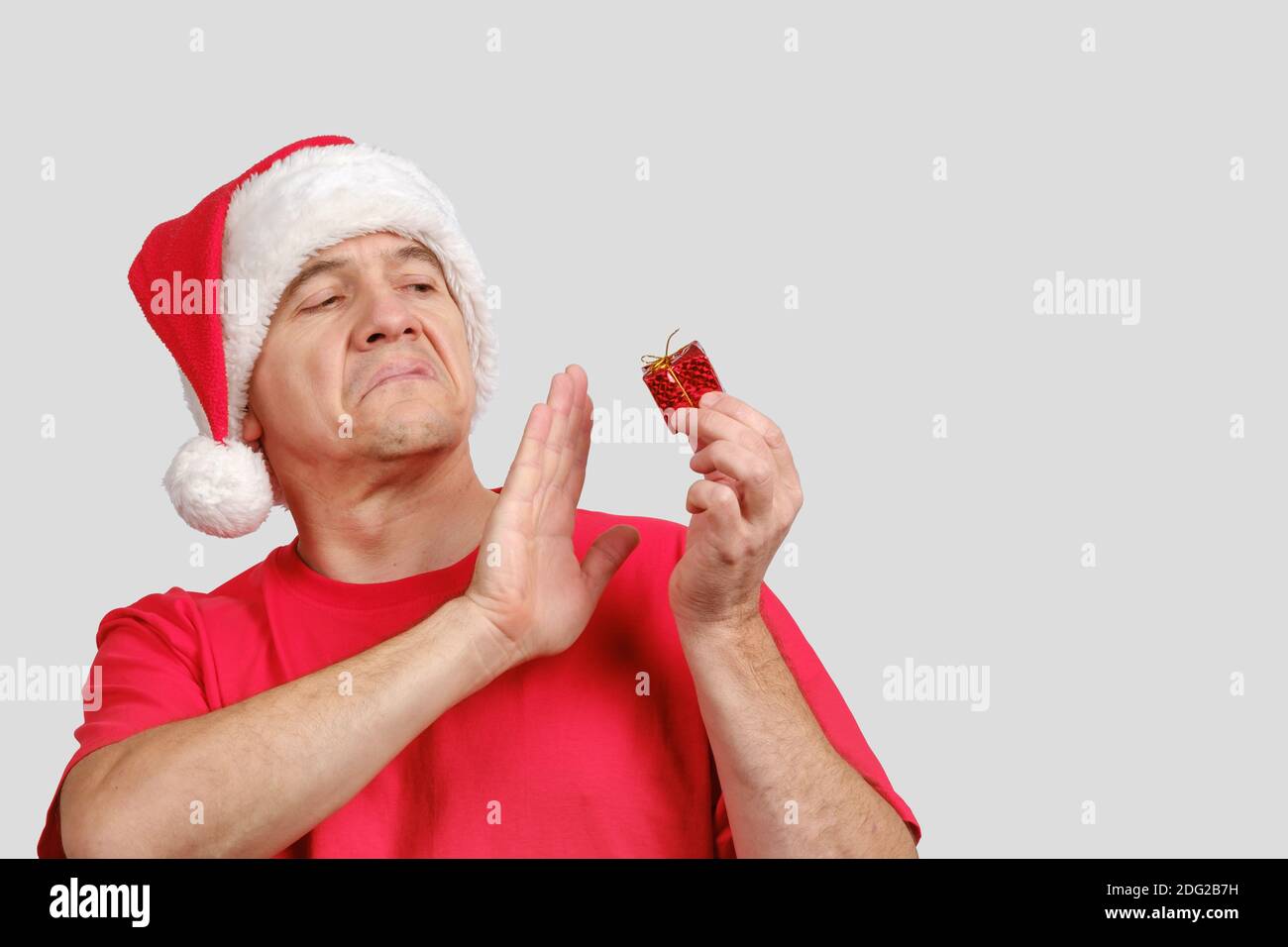 Enttäuschung Mann mittleren Alters in Santa Hut hält schlechte kleine Weihnachten Geschenk Stockfoto