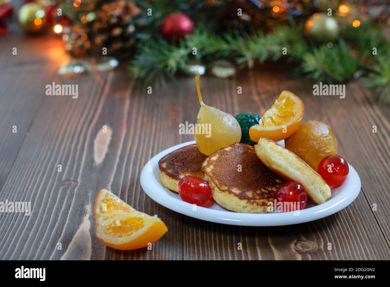 Traditionelle japanische flauschige Pfannkuchen mit Sortiment von glasierten Früchten auf der weißen Platte, auf dem weihnachtlichen Hintergrund. Köstliches Frühstück ein festliches Stockfoto