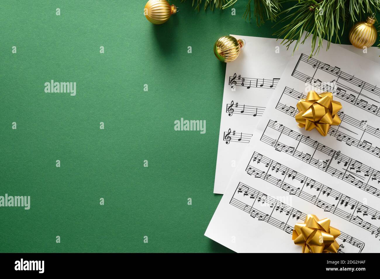 Blank für Weihnachten Weihnachtslieder und singt geschmückt goldenen Kugeln auf grünem Hintergrund. Blick von oben. Stockfoto