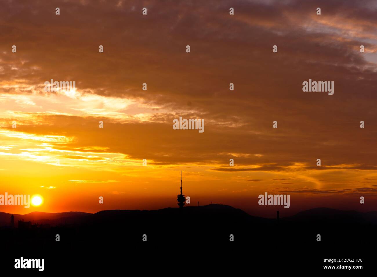 Abendszene eines städtischen Gebietes mit roten Wolken und Silhouetten der Berge Stockfoto