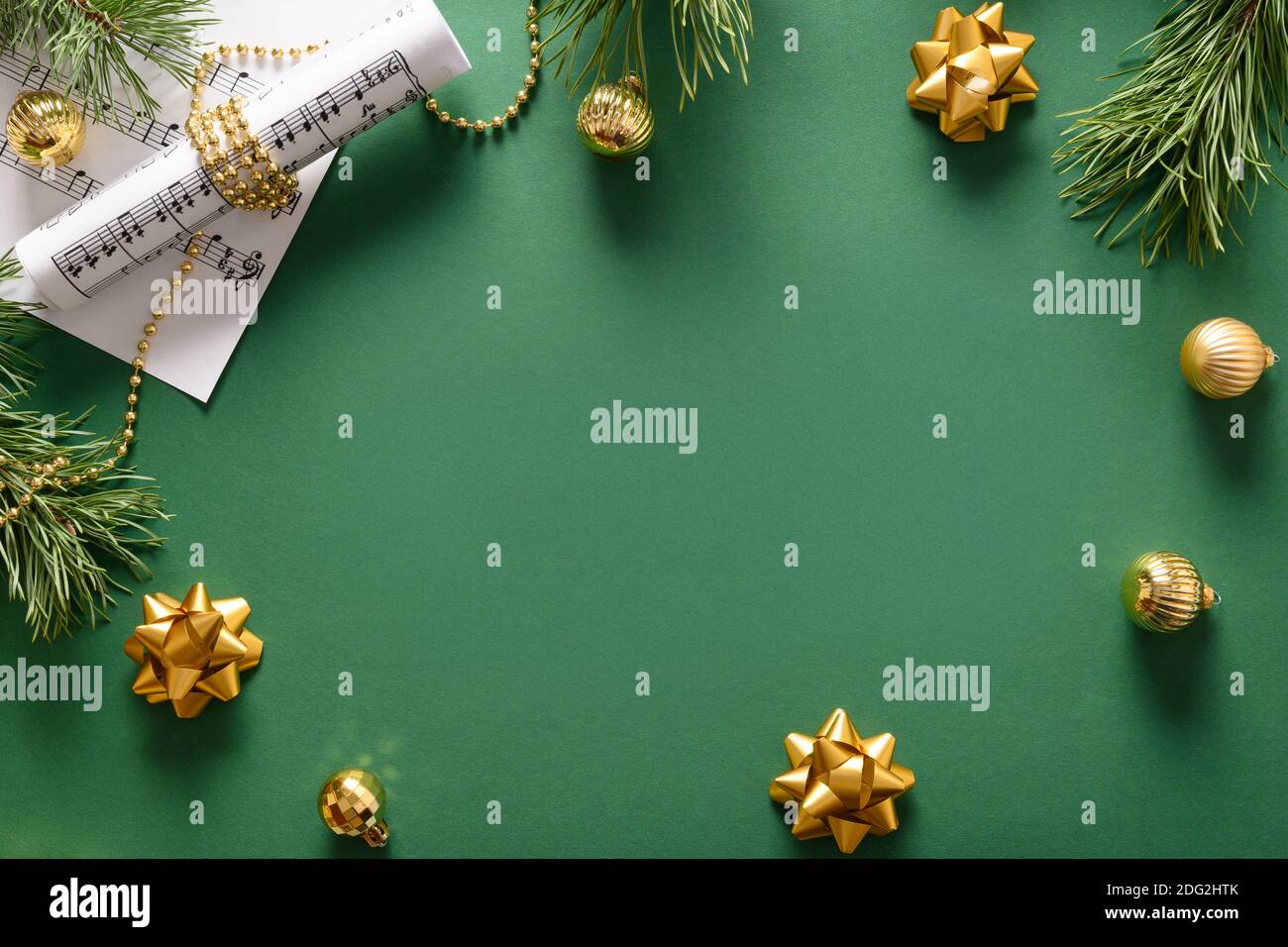 Musikrahmen für Weihnachten Weihnachtslieder und singt geschmückt goldenen Kugeln auf grünem Hintergrund. Blick von oben. Leerzeichen für Text. Stockfoto