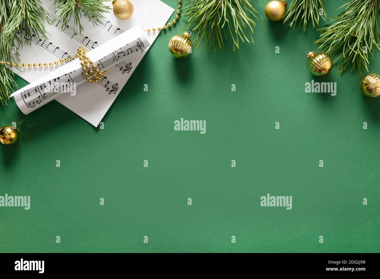 Musik Weihnachtskomposition für Weihnachtslieder und Lieder verziert goldene Kugeln auf grünem Hintergrund. Blick von oben. Leerzeichen für Text. Stockfoto