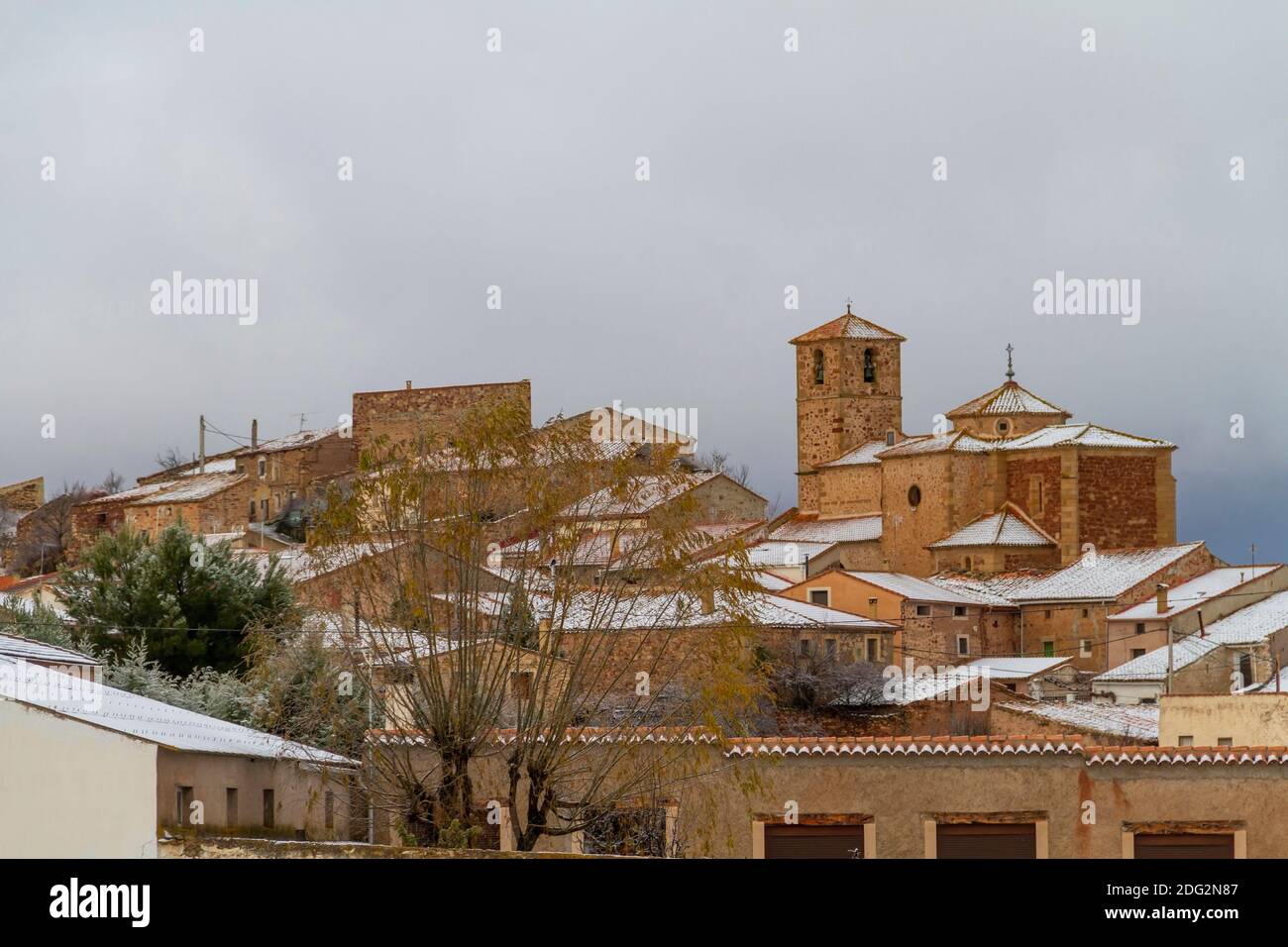Blick auf die verschneite Stadt Castellar de la Muela in der Provinz Guadalajara, Landkreis Molina-Alto Tajo, mit dem Turm der Kirche von N.ª S.ª de la Ca Stockfoto
