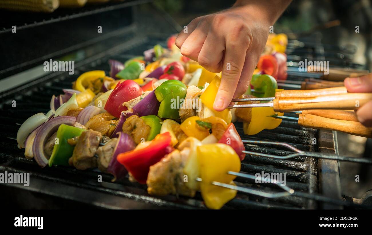 Hand des Mannes mit Grill. Kochen Sie einen leckeren Spieß auf gegrilltem Fleisch. Essen gekocht mit Grillen Grill. Koch Kochen Brochette im Hinterhof eines Hous Stockfoto