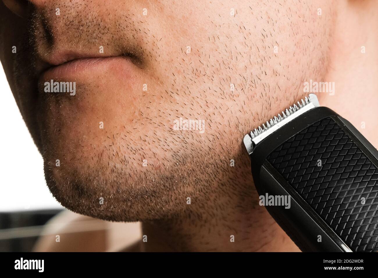 Der Mann schneidet sich den Bart mit einem elektrischen Trimmer Stockfoto