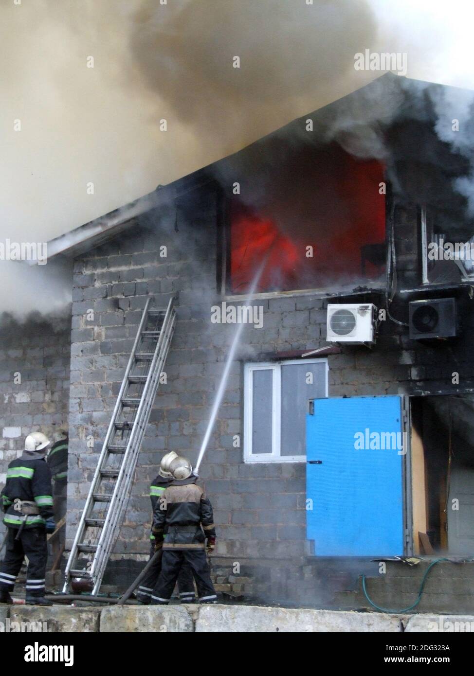Feuerwehrleute reagieren auf einen Brand in einem großen Gebäude, das von einem Feuer erfasst wird In Flammen Stockfoto