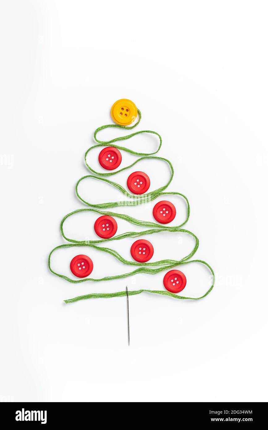 Nähthema kreatives Flat Lay Design: Weihnachtsbaum aus Nadel, Faden und Knöpfen auf weißem Hintergrund Stockfoto