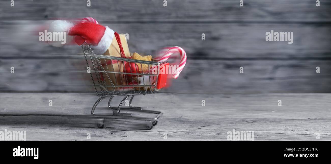 Schnell kleinen Warenkorb mit Geschenken, weihnachtsdekoration, Süßigkeiten und Weihnachtsmann Hut ist auf rustikalen Holzplanken für Last Minute Online fahren gif Stockfoto