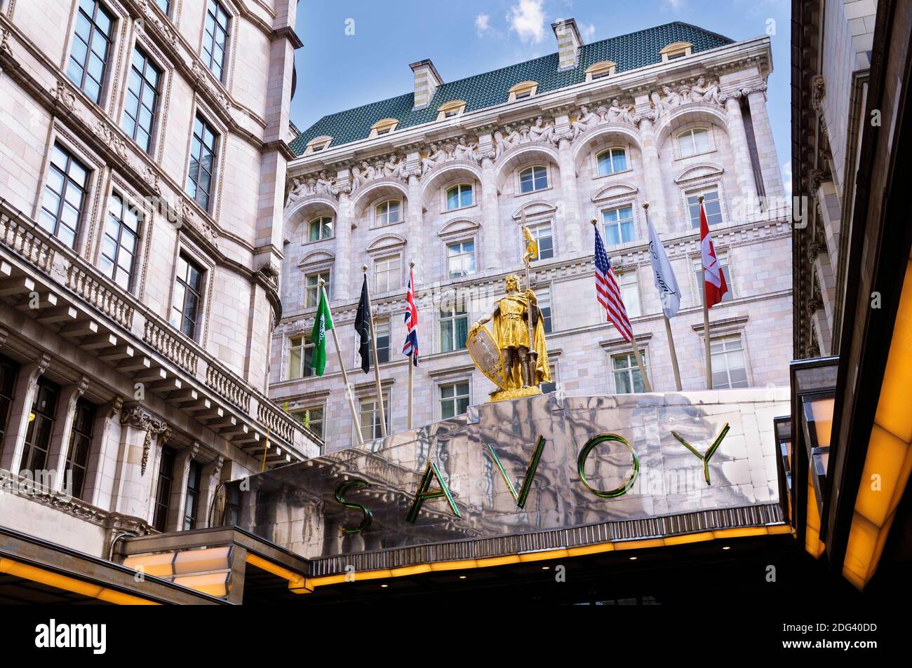 The Savoy Hotel, London, England, Großbritannien. Vergoldete Statue von Peter II Graf von Savoyen neben Flaggen über dem Eingang des berühmten Luxus-5-Sterne-Hotels. Stockfoto