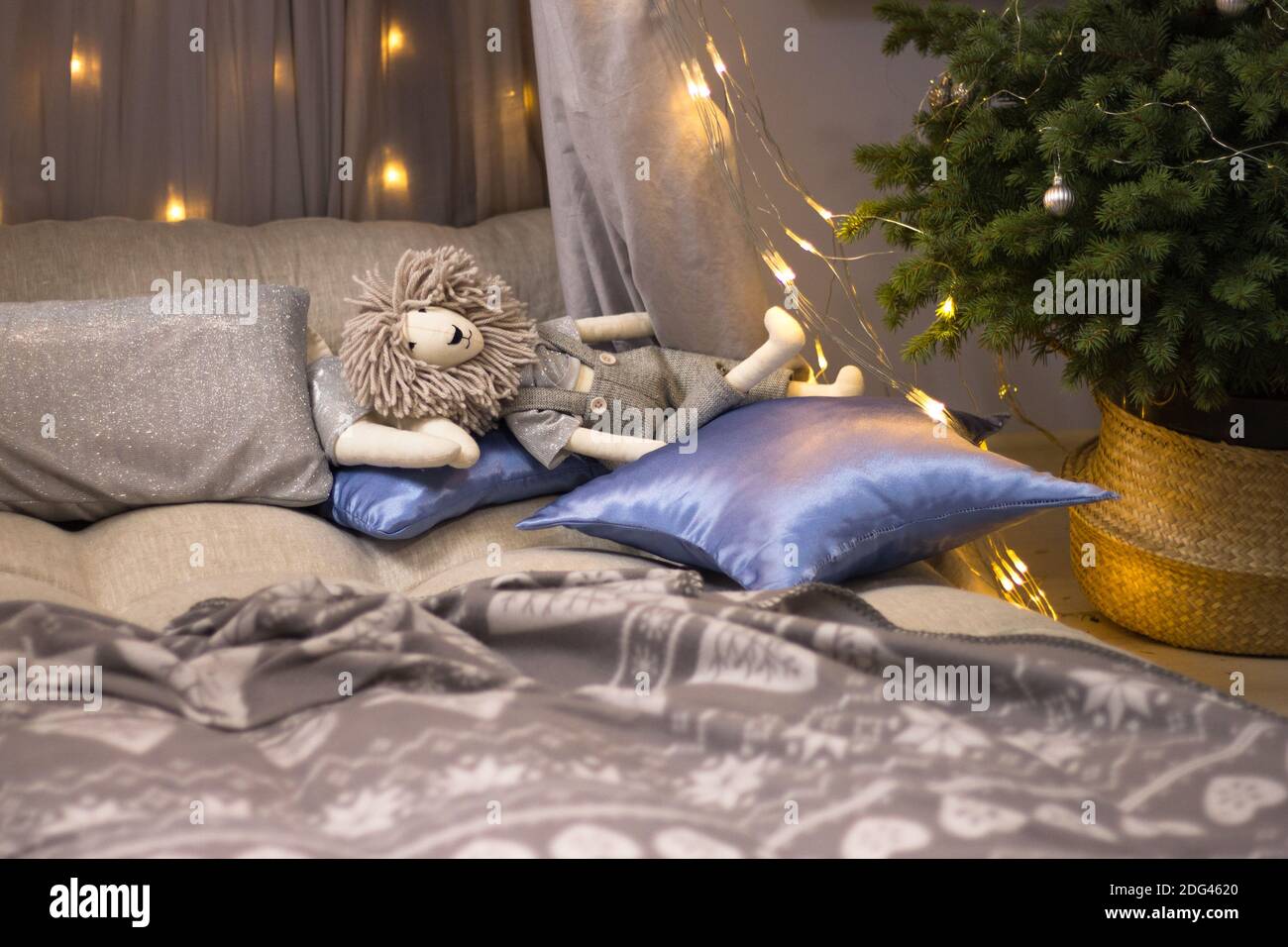 Spielzeug Löwe ruht auf Kissen auf einem Kinderbett mit Ein Baldachin mit Lichtern und einem Weihnachtsbaum geschmückt Stockfoto