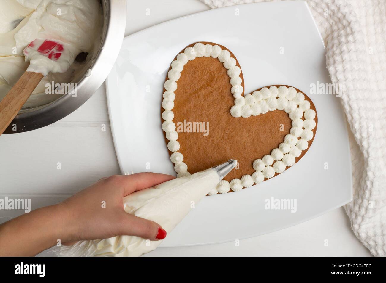 Schritt-für-Schritt-Rezept für herzförmige Kuchen. Schritt 10: Die Sahne mit einem Tütchen auf die Kuchen auftragen. Flach liegend. Stockfoto