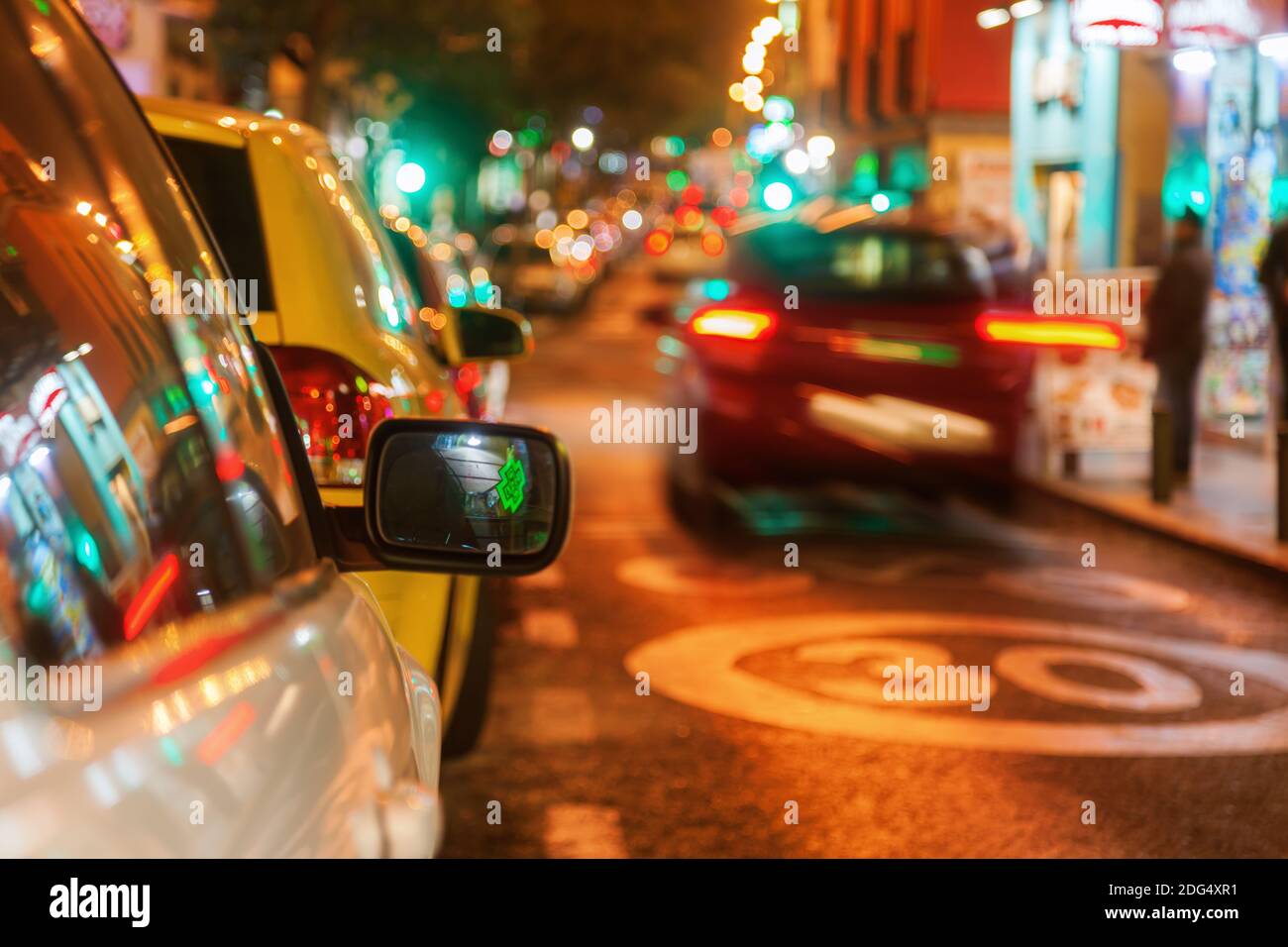 Straßenlandschaft bei Nacht mit enger Schärfentiefe Und konzentrieren Sie sich auf einen Rückspiegel eines Parkwagens Stockfoto