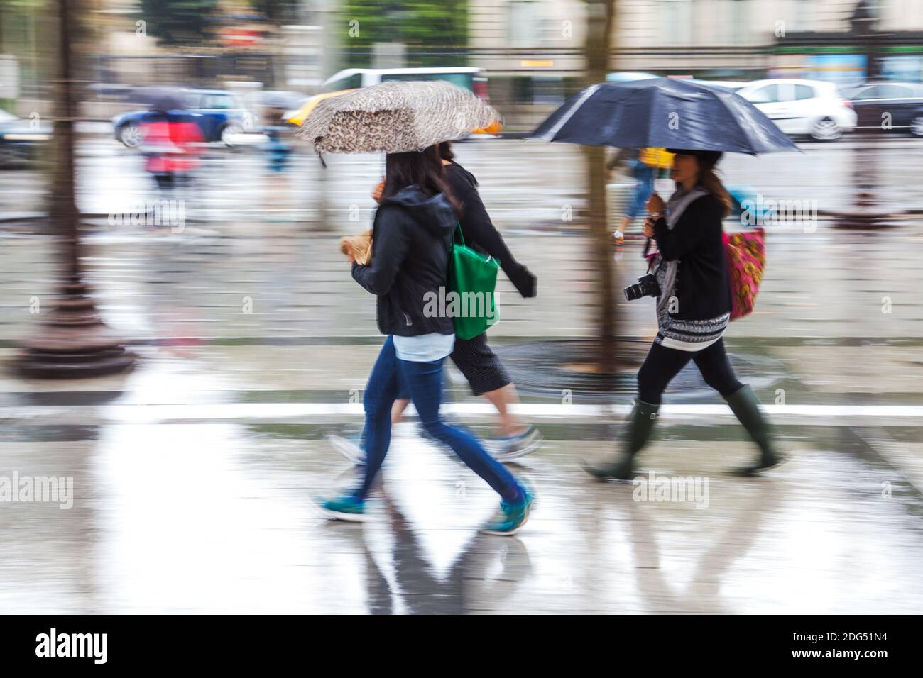 Frauen mit Regenschirmen laufen in der regnerischen Stadt Bewegungsunschärfe Stockfoto