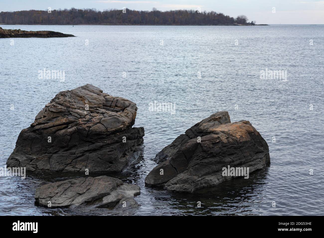 Geriebene, erodierte Felsbrocken zeigen die Spuren der Gezeiten entlang der Küste des Long Island Sound im Pelham Bay Park, Bronx, NY Stockfoto