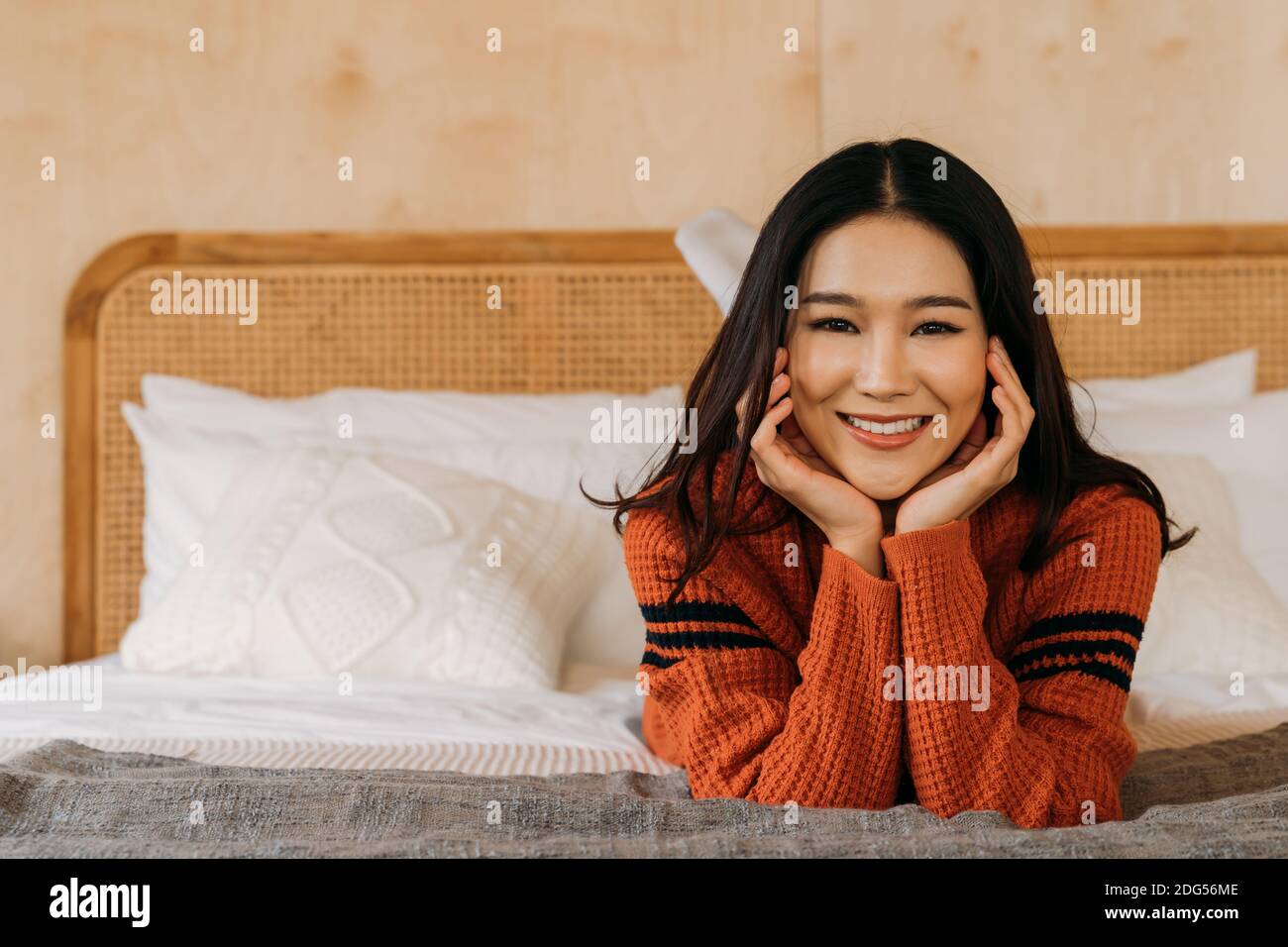 Junge Teenager asiatische Frau trägt einen Pullover mit hübschen Lächeln Blick auf Kamera im Schlafzimmer. Attraktive Mädchen mit Gesichtsbehandlung und gesunde Schönheit Haut Winter Portrait Mode Lifestyle. Bannerbereich. Stockfoto