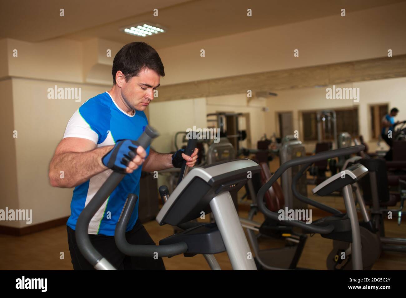 Mann am Crosstrainer im Fitness-Studio trainieren Stockfoto