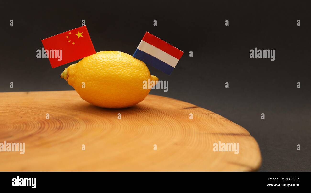 Niederlande - Niederländische und chinesische Flaggen, die aus einem Zitrone auf einem Hackblock, der die angespannte seelengeschüpfte Beziehung darstellt Und Handelskrieg als Lohn Stockfoto