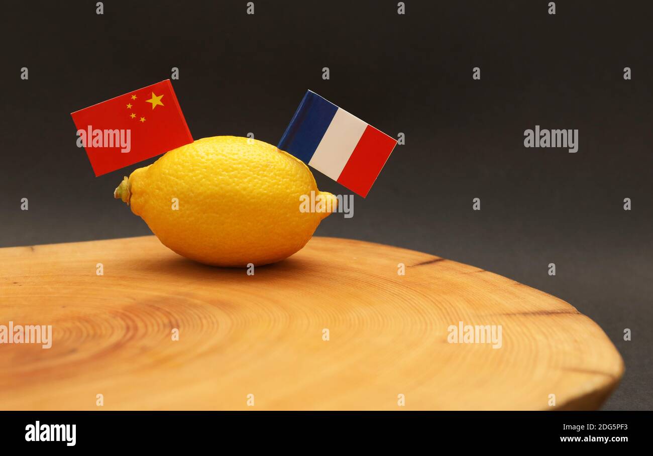 Französische und chinesische Flaggen, die aus einer Zitrone stossen Ein Zerkleinerungsblock, der die angespannte, seelengespannte Beziehung und den Handel darstellt Krieg zwischen den Stockfoto