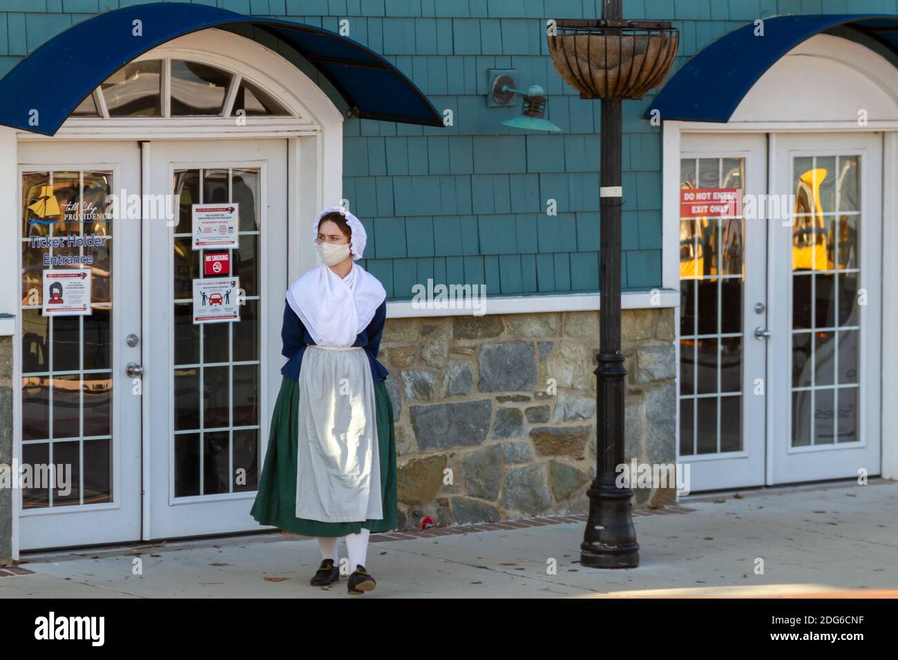 Alexandria, VA, USA 11-28-2020: Eine Restaurantangestellte mit einem kolonialen Frauenkostüm und einer Gesichtsmaske aufgrund von COVID-19 wartet auf den Stockfoto