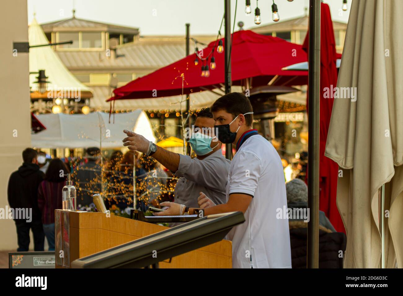 Alexdandria, VA, USA 11-28-2020: Ein Restaurantbesitzer mit Handschuhen und Gesichtsmaske wegen COVID-19 spricht mit der Empfangsdame, die auf Kunden wartet Stockfoto