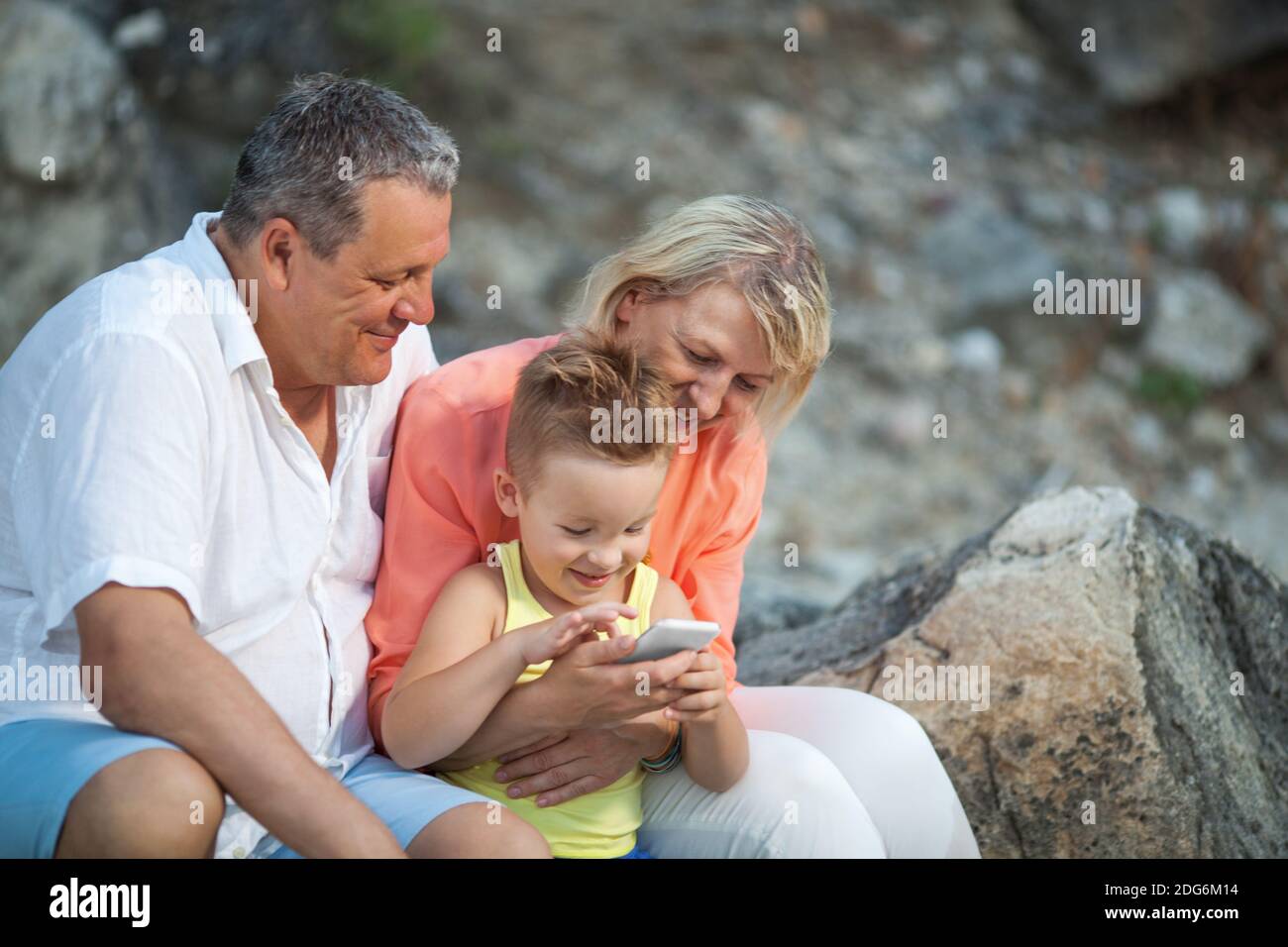 Glücklicher Junge mit Handy und Großeltern im Freien Stockfoto