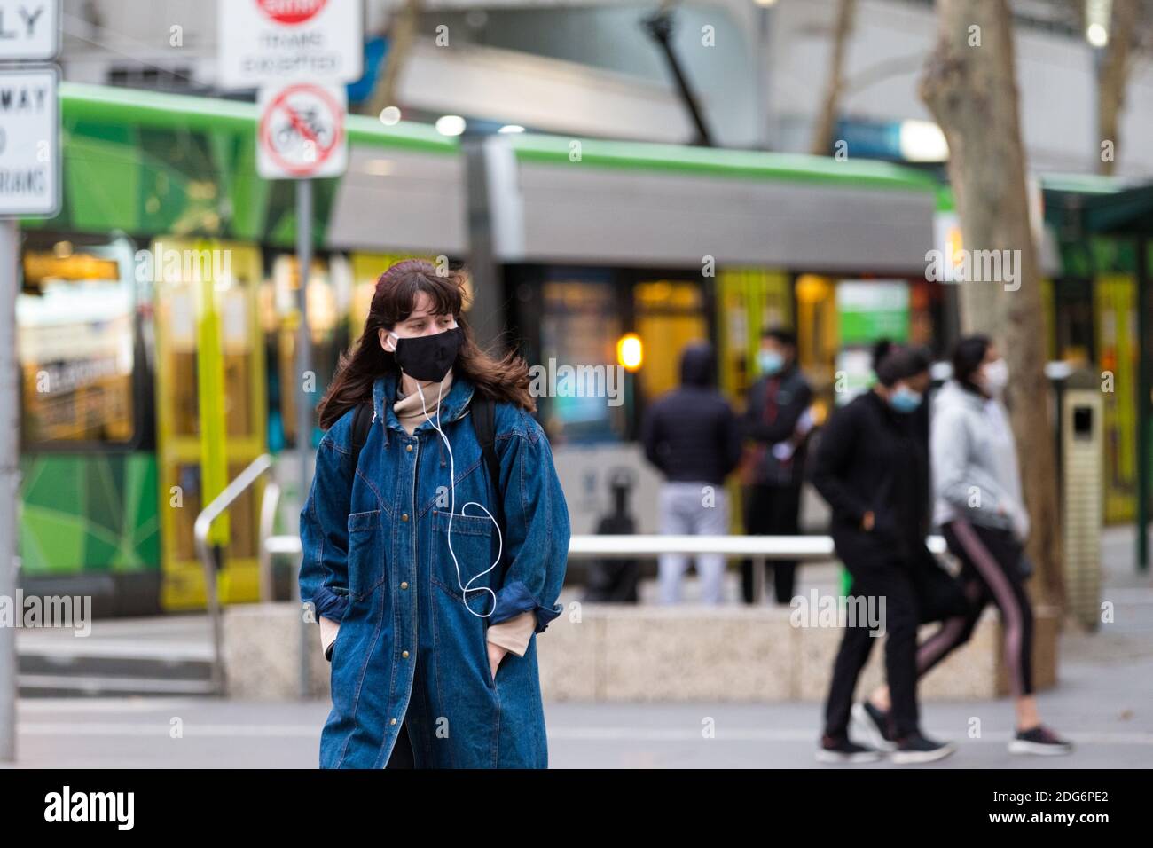 Melbourne, Australien, 7. August 2020. Ein Blick auf die Straßenbahnhaltestelle in der Bourke Street, wo eine Frau die Straße überquert, während sie eine Maske trägt und während der COVID-19 in Melbourne, Australien, Musik hört. Die Einschränkungen der Stufe 4 in Melbourne werden fortgesetzt, da das Leben von der Stadt abfliesst, jetzt, wo Arbeitsgenehmigungen durchgesetzt werden. Premier Daniel Andrews hat erneut nicht auf Fragen zu Misserfolgen in seiner Regierung, die zu über 180 Todesfällen in seinem Staat führte, antworten können. Victoria verzeichnete weitere 450 neue COVID-19 Infektionen sowie 11 Todesfälle über Nacht.Quelle: Dave Hewison/Alamy Live News Stockfoto