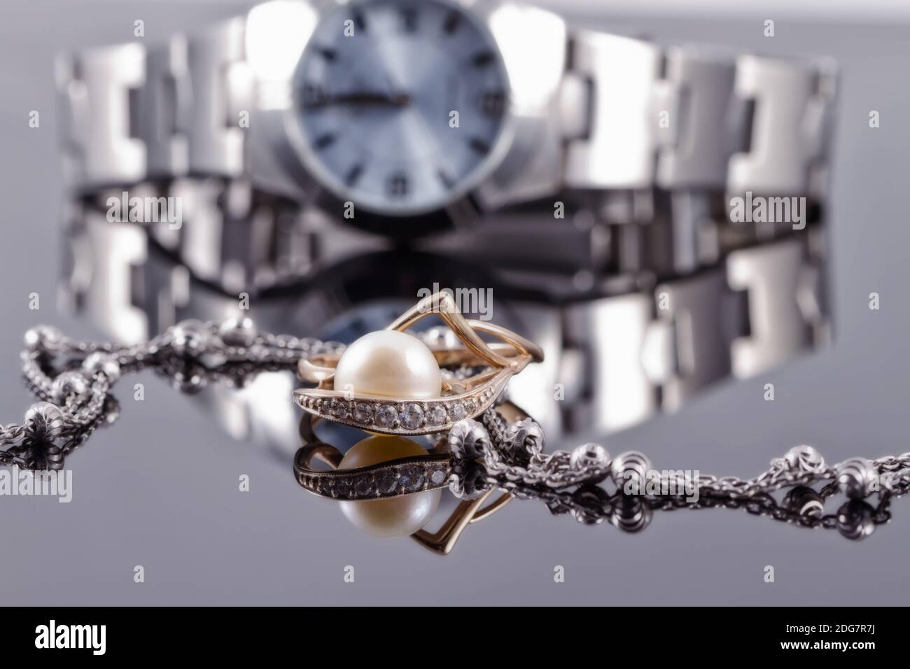 Goldring mit Perlen und silberner Kette auf dem Hintergrund Uhren Stockfoto