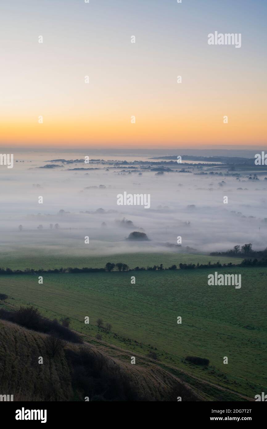 Nebel bei Sonnenuntergang über der Landschaft von wiltshire vom Roundway Hill in den Wessex Downs. Vale of Pewsey, Wiltshire, England Stockfoto