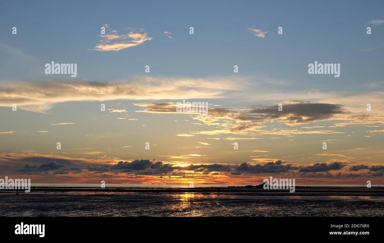 Schöner Sonnenuntergang Himmel mit Wolken und Küste am fernen Horizont. Stockfoto