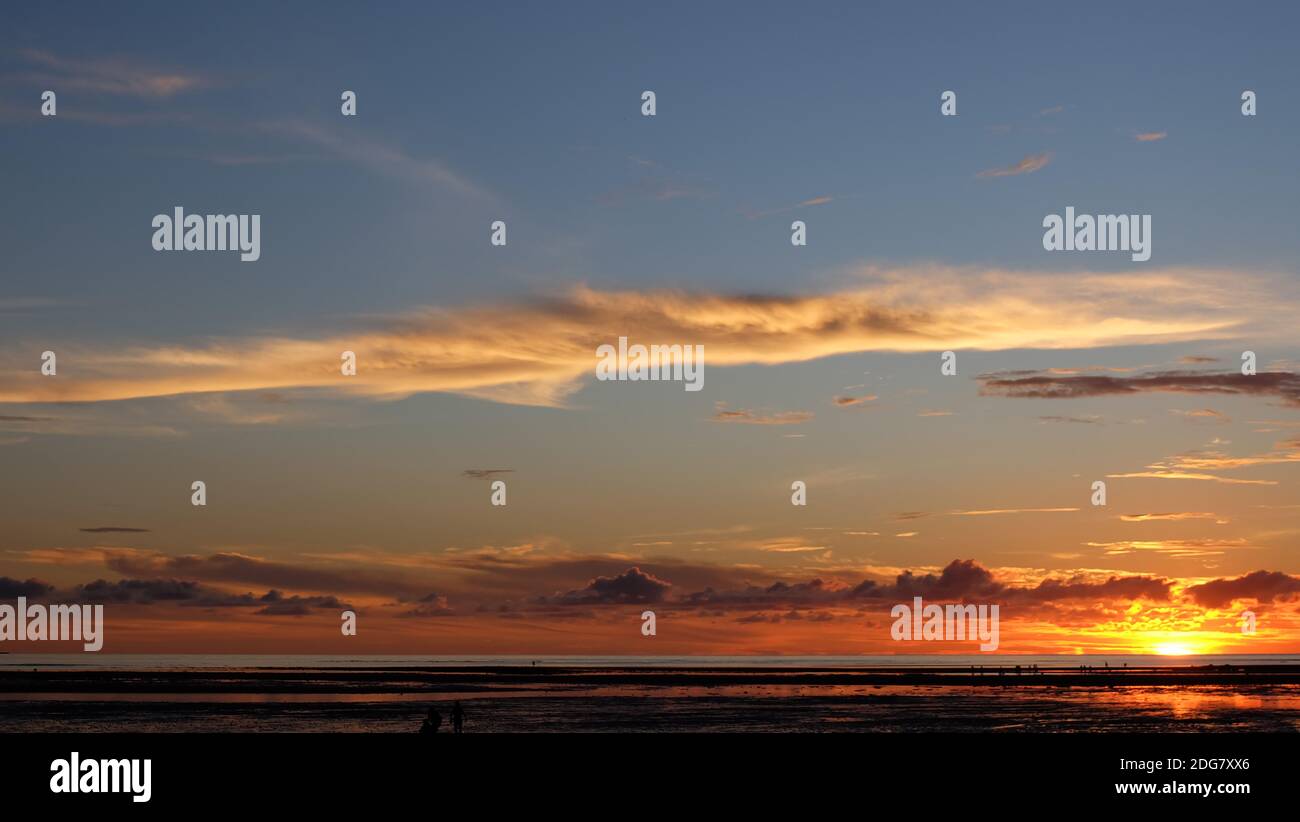 Schöner Sonnenuntergang Himmel mit Wolken und Küste am fernen Horizont. Stockfoto