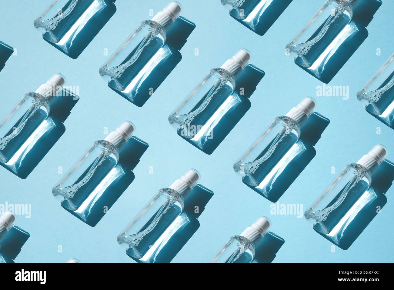 Trendiges Muster von Sprays mit alkoholischen Antiseptikum, Desinfektionsmittel auf blauem Hintergrund. Flach liegend, harter Schatten von der Sonne. Antivirenschutzkonzept Stockfoto